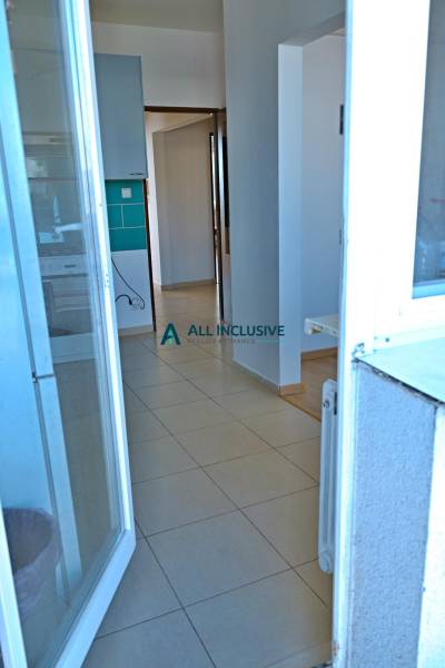 A view into the hallway of a 3-room apartment with tiles and a kitchen view.