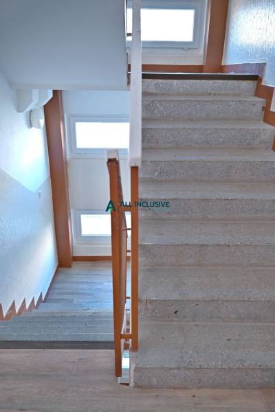 A staircase in a 3-room apartment with wooden railing and windows for natural light.