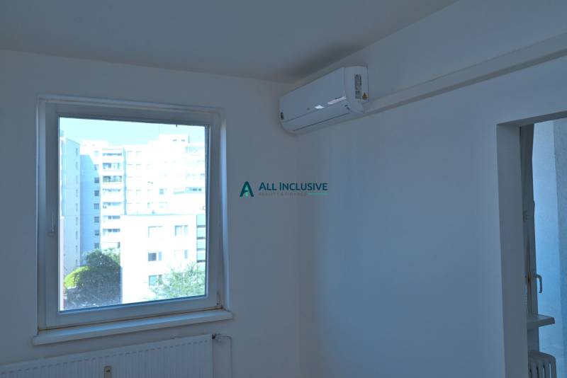A room in a 3-room apartment with a window and air conditioning, view of apartment blocks.