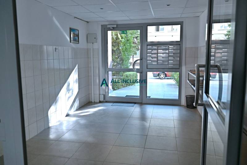 Entrance hallway of an apartment building with mailboxes and glass doors.