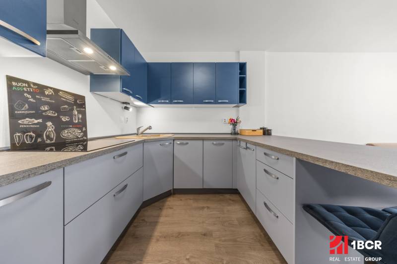 A kitchen in a 2-room apartment with light furniture and dark blue cabinets.