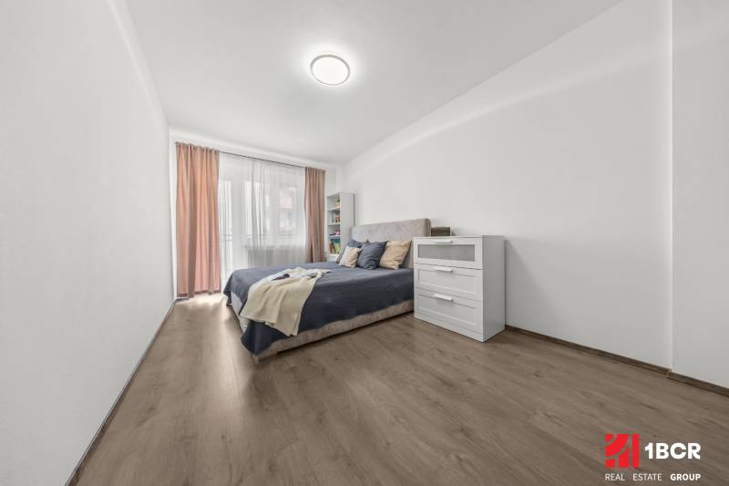 Bright bedroom with a bed and a dresser in a 2-room apartment.