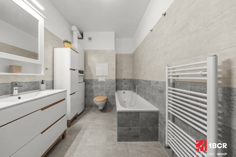 Bathroom with a sink, bathtub, toilet, and ladder radiator in a 2-room apartment.