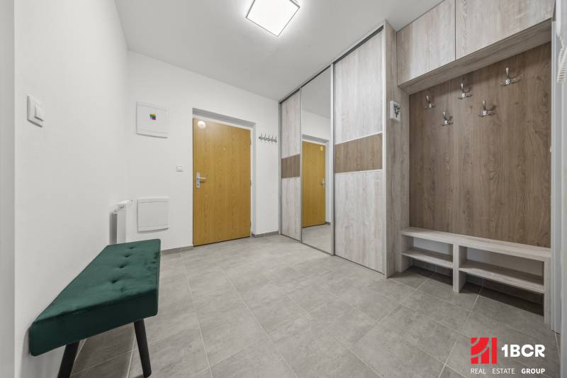 Entrance hallway with wooden furniture and a green bench in a 2-room apartment.