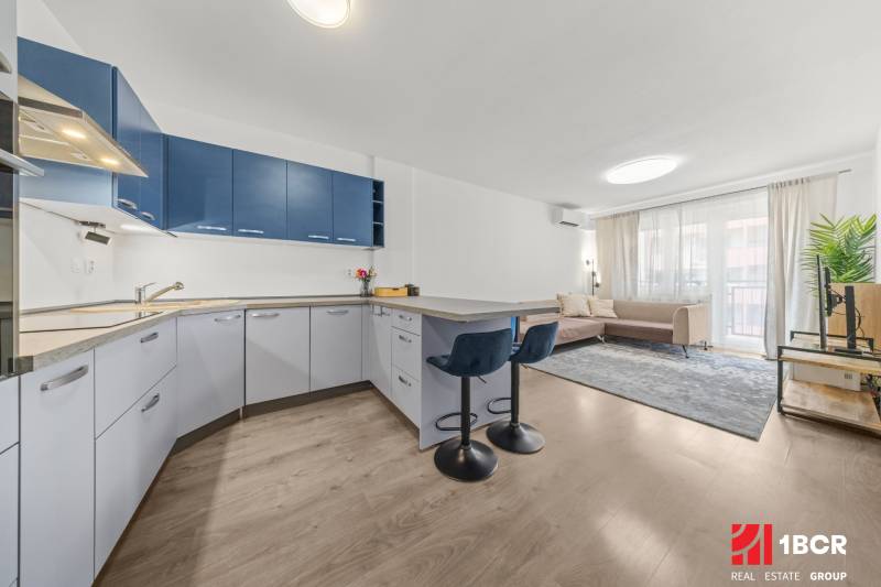 Kitchen with living area and bar stools in a 2-room apartment.