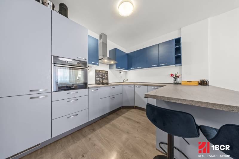 A kitchen in a 2-room apartment with modern appliances and bar stools.
