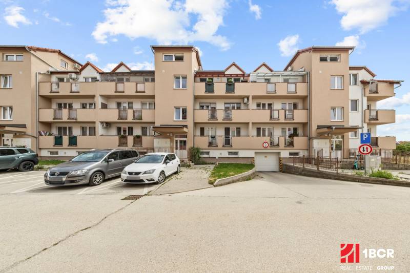 Apartment building on Dona Sandtner Street in Pezinok with parking spaces in front of the building.