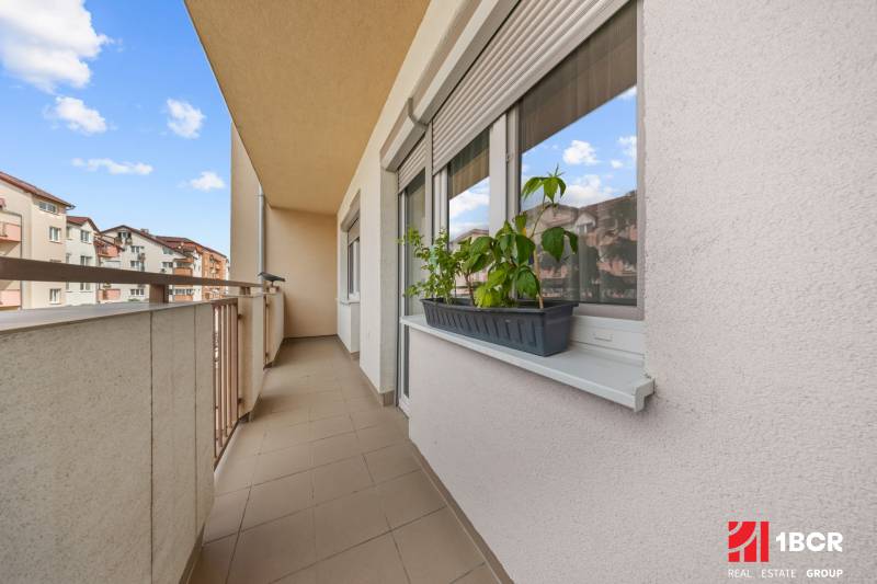 The balcony of a 2-room apartment on Dona Sandtnera Street in the town of Pezinok, with flowers on the windowsill.