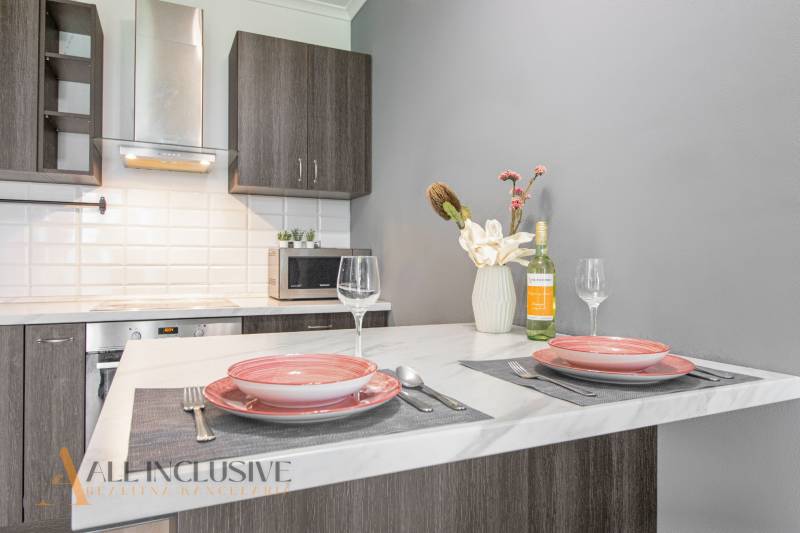 The kitchen in a 2-room apartment with a dining counter, dishes, and wine on the table.