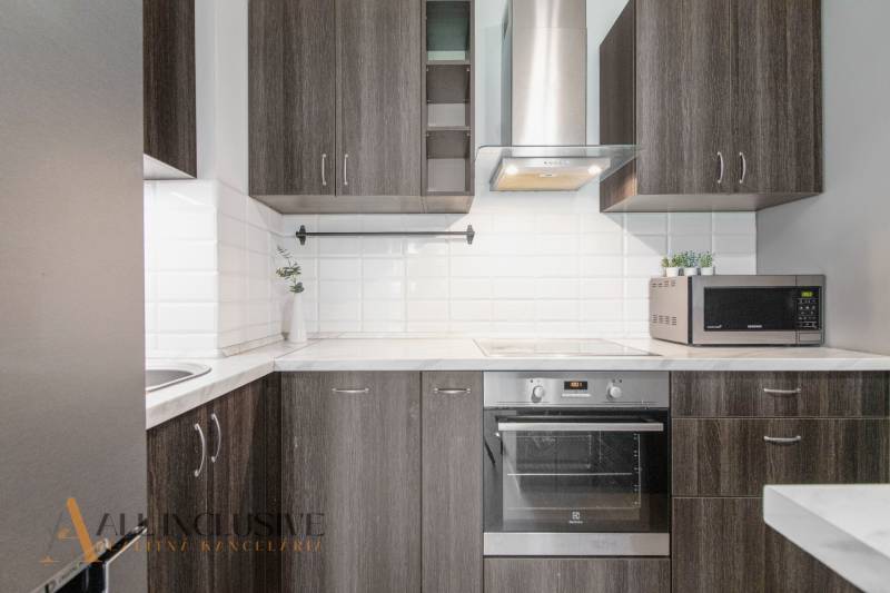 Kitchen in a 2-room apartment with appliances and wooden cabinets, white tiles.