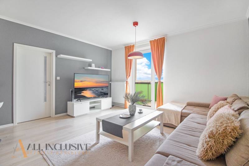 A bright living room in a two-room apartment with a balcony and a comfortable sofa.