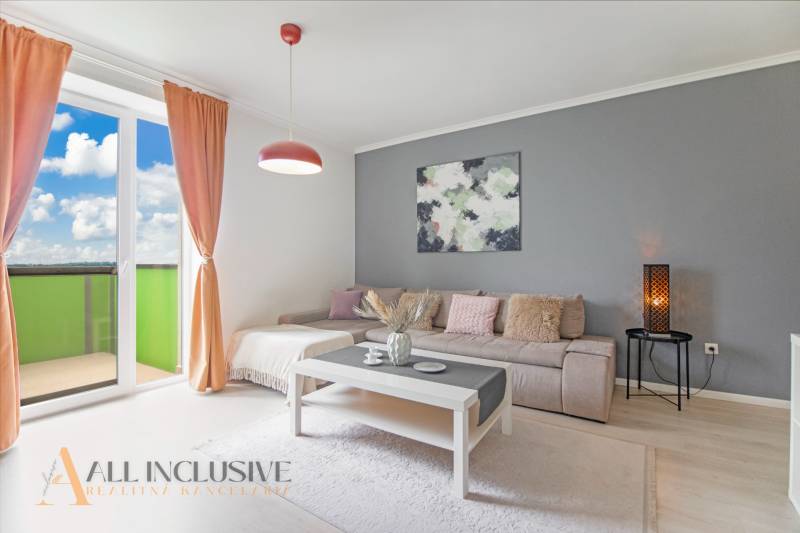 Living room in a two-room apartment with a sofa, table, and balcony.