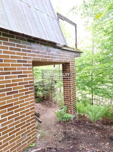 A cottage in Kokava nad Rimavicou with a brick facade amidst a forest scenery.