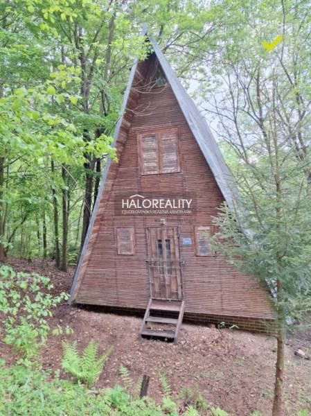 A wooden cabin in the forest near Kokava nad Rimavicou with a triangular roof and a peaceful surroundings.