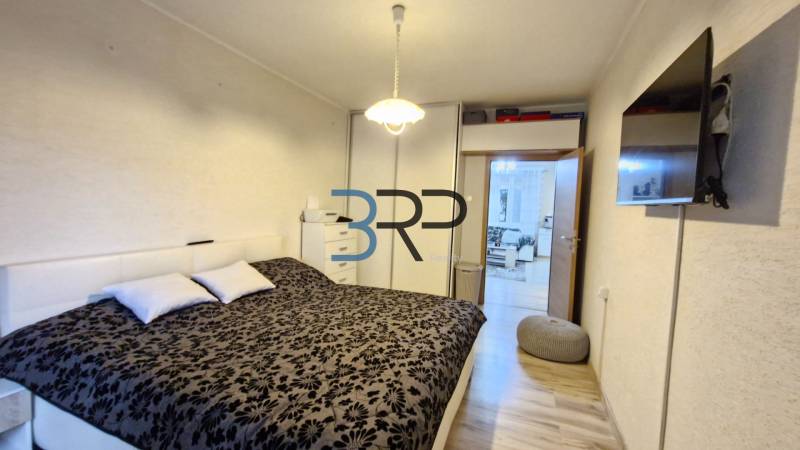 Cozy bedroom in a 3-room apartment with a large bed and a TV on the wall.