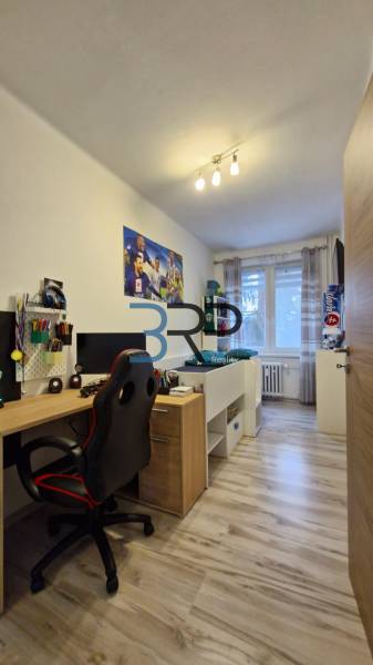Room and a 3-room apartment with a desk, chair, and bed by the window.