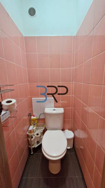 A toilet with pink tiles located in a 3-room apartment.