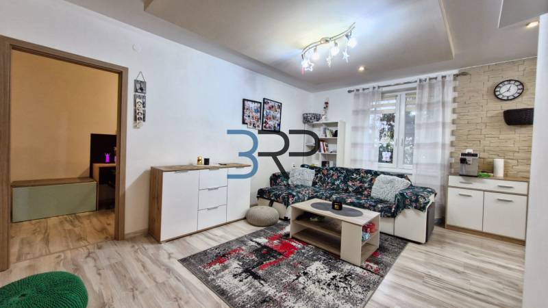 Living room with a decorative wall, wooden furniture, and flooring in a three-room apartment.