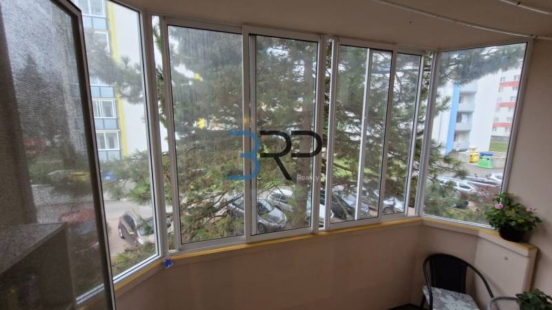 Enclosed balcony with glazing in a 3-room apartment, view of the surrounding street.