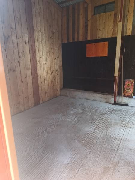 Wooden interior of a cabin with a concrete floor and wooden walls.