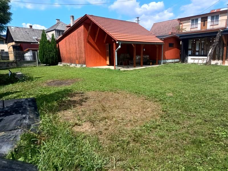 A cottage in Tužina with a wooden extension and a green yard.
