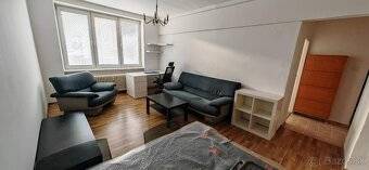 Living room in a two-room apartment with a sofa and windows with a view.