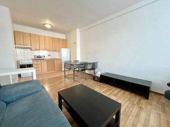 Living room with kitchen in a two-room apartment with a sofa and a dining table.