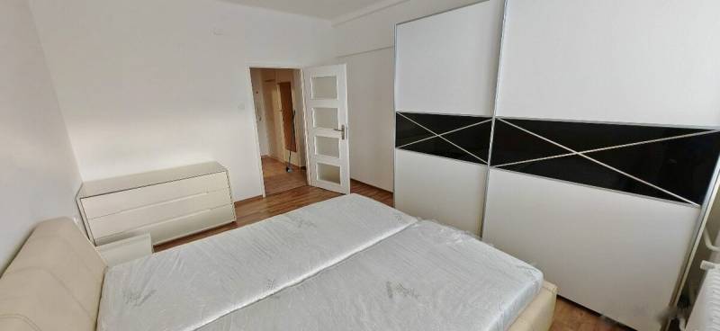 Bedroom in a 2-room apartment with a bed, wardrobe, and dresser, light wooden floors.