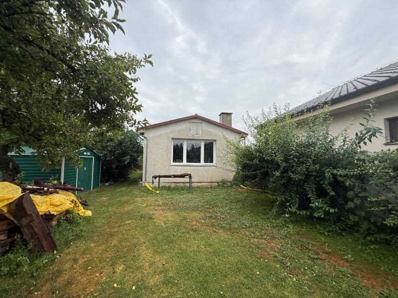 A garden at a family house in Ludanice with a lawn, trees, and a metal shelter.