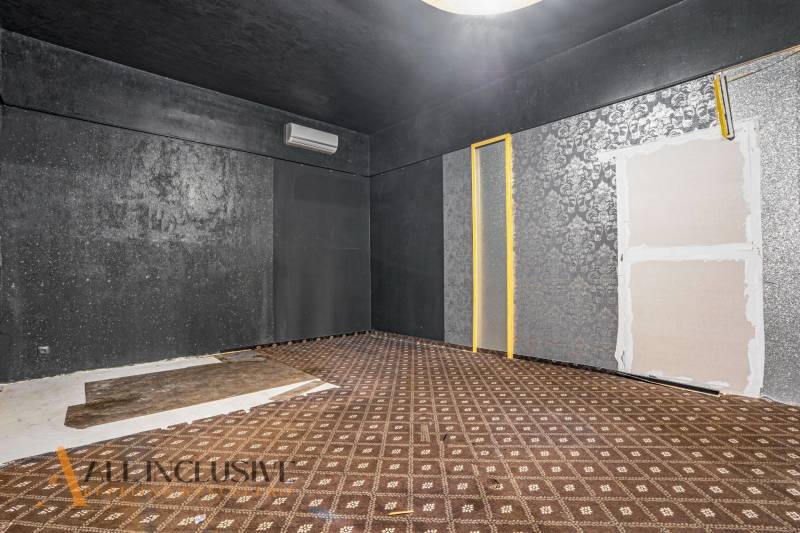 The interior of commercial spaces with dark walls and patterned carpet.