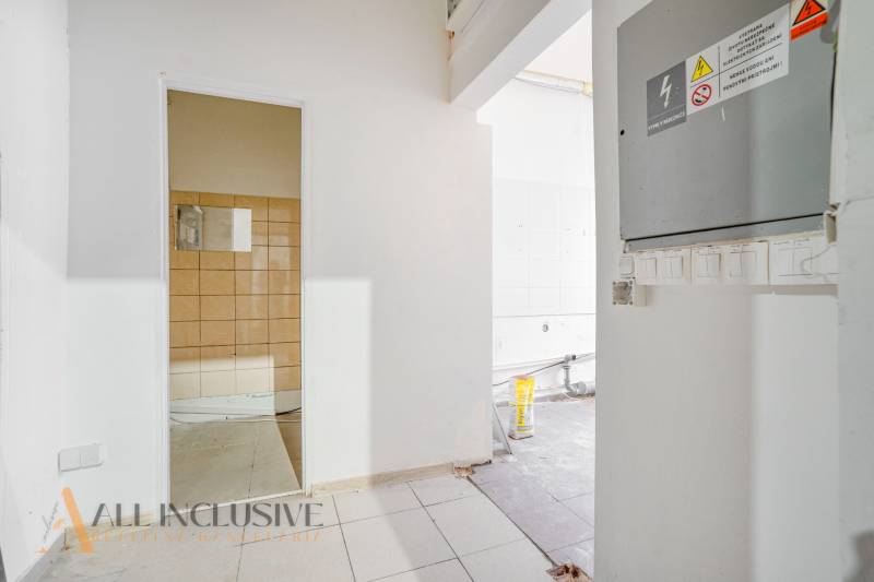 Unfinished commercial spaces with visible electrical installations, white and brown tiles.
