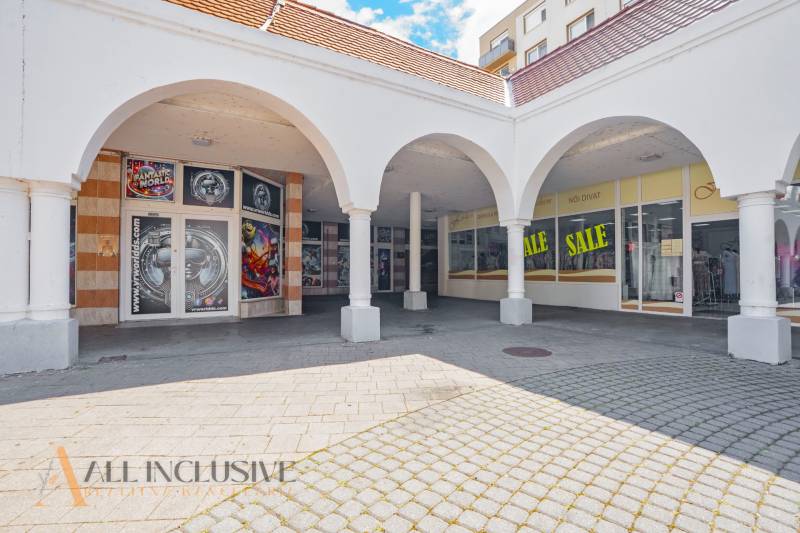 Commercial spaces in Dunajská Streda with arched arcades and advertising for discounts.