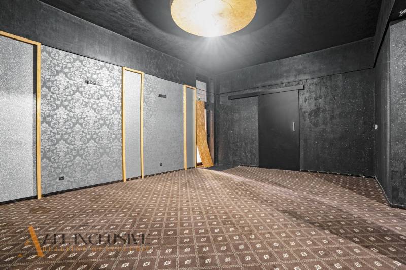 Commercial space with dark walls, patterned carpet, and a large light on the ceiling.