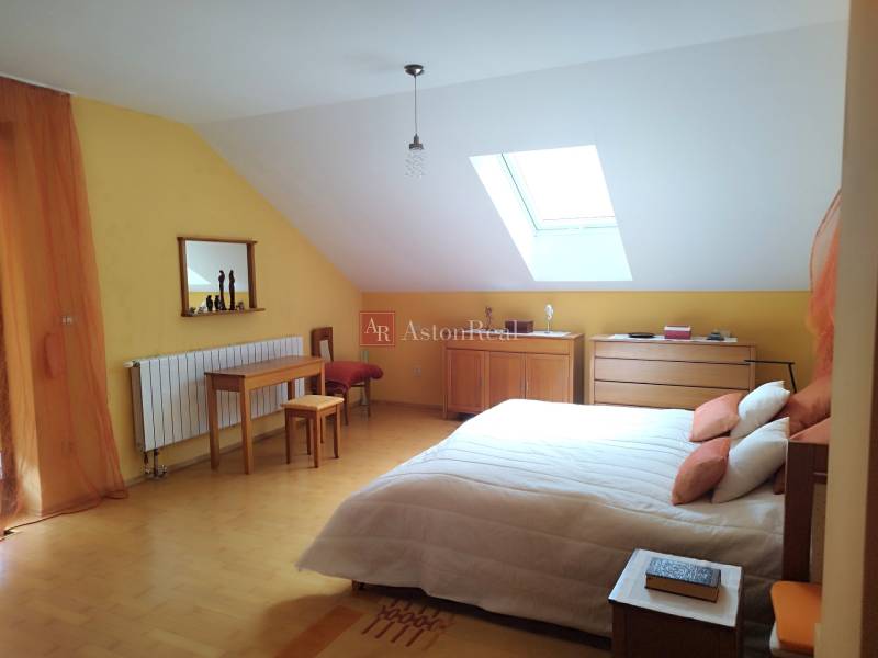 Attic bedroom in a family house with wooden furniture and a skylight.
