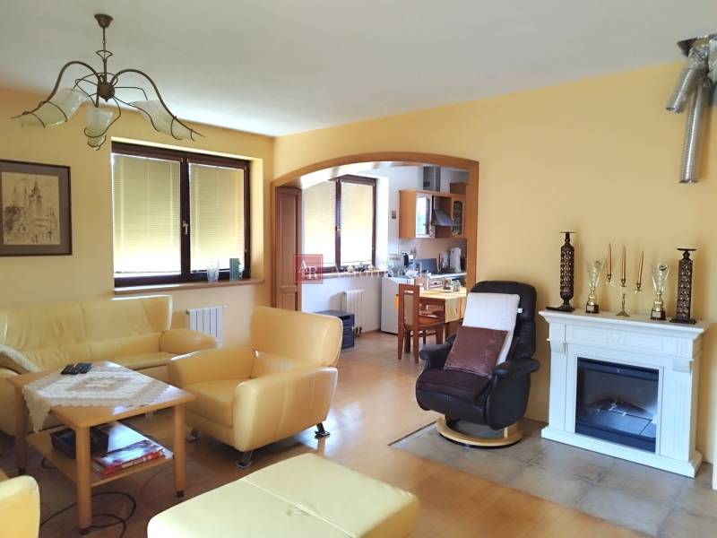 Living room in a family house with a fireplace, yellow sofas, and access to the kitchen.