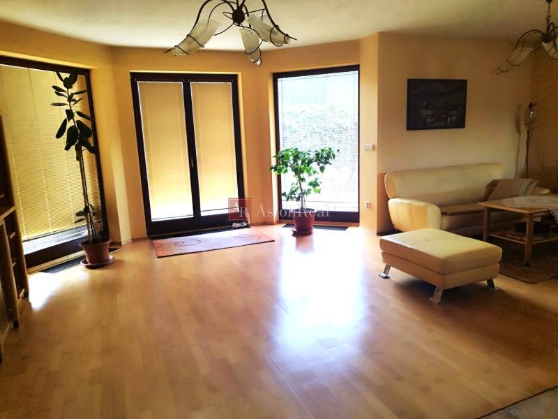 Living room in a family house with wooden flooring, a sofa, and plants.