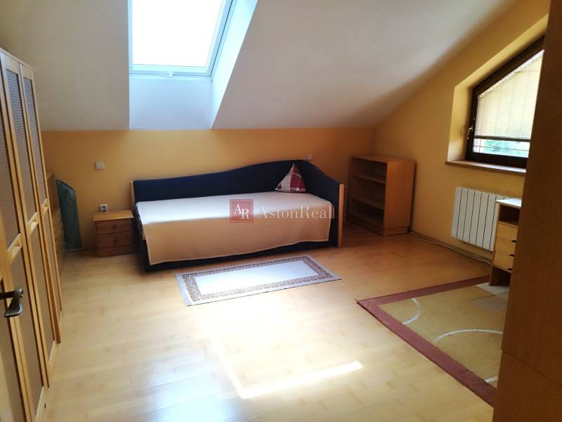 Attic room with a bed, wardrobe, and table in a family house.