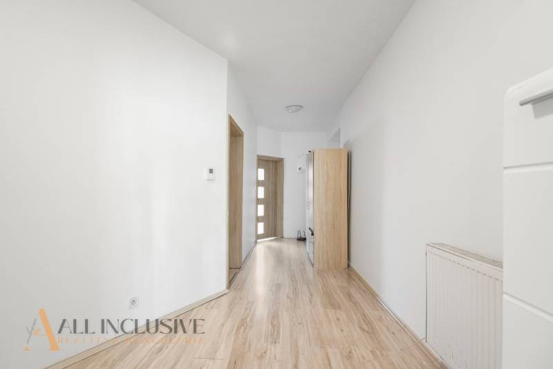 A hallway in a family house with wooden flooring and light-colored furniture.