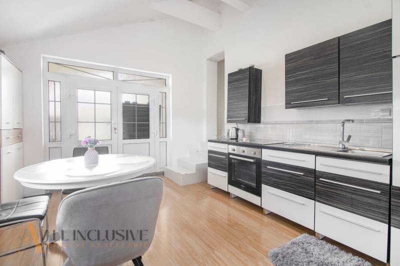 A kitchen in a family house with modern equipment, a white table, and glass doors.