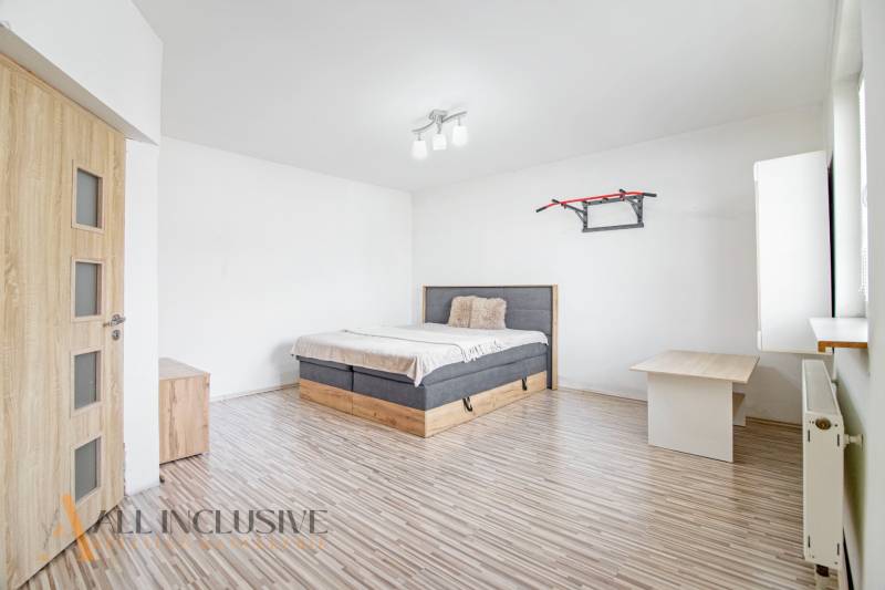Bright bedroom in a family house with wooden flooring and a bed.