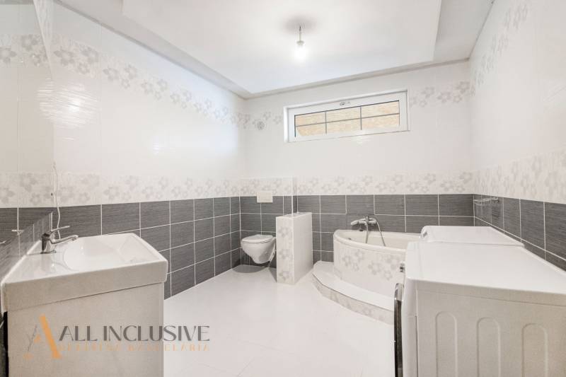 Bathroom in a family house with a bathtub, sink, toilet, and washing machine.
