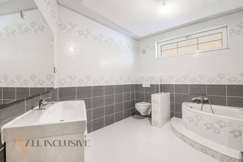 Bathroom with a bathtub, toilet, and sink in a family house, bright and simple design.