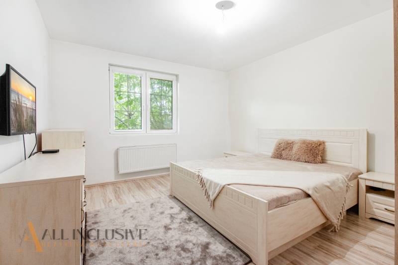 A bright bedroom with a bed, television, and window in a family house.