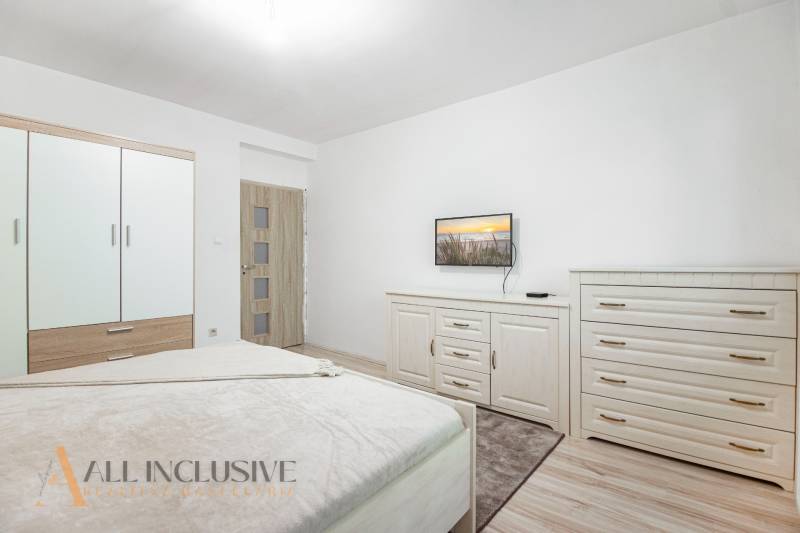 Bright bedroom with a bed, wardrobe, dresser, and television in a family house.