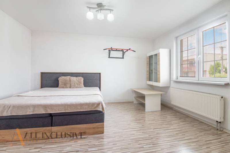 Bright bedroom in a family house with a bed, shelf, and large window.