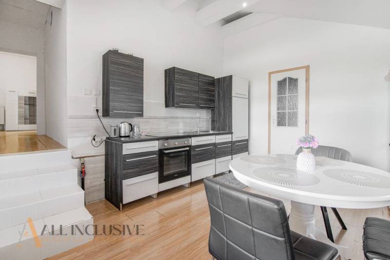 A kitchen in a family house with dark furniture and a white table with decoration.