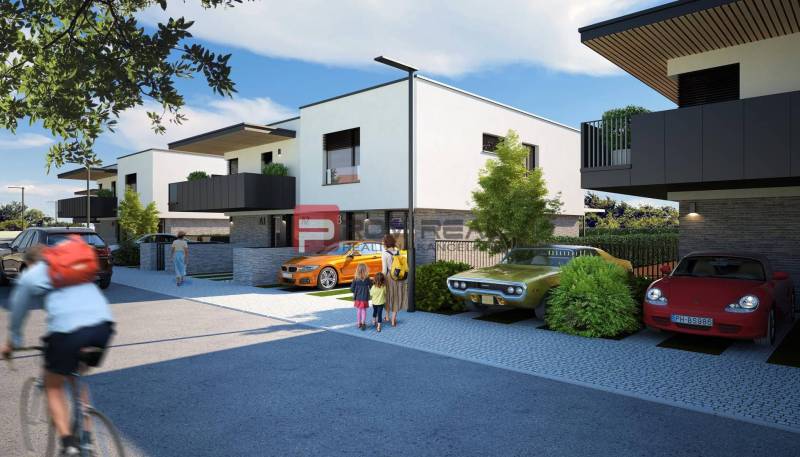 Newly built 3-room apartments in Dubová, surrounded by cars and cyclists in sunny weather.