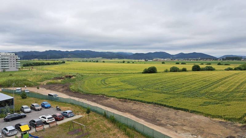 View from a studio apartment on Suchoňova Street in Poprad, with a field and cars.