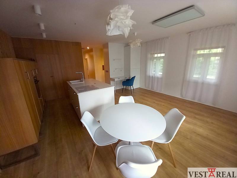A kitchen with an island and a dining table in a family house, light walls and wooden floors.