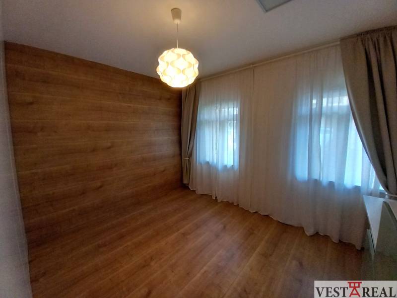 A room in a family house with wooden paneling, flooring, and a ceiling light.